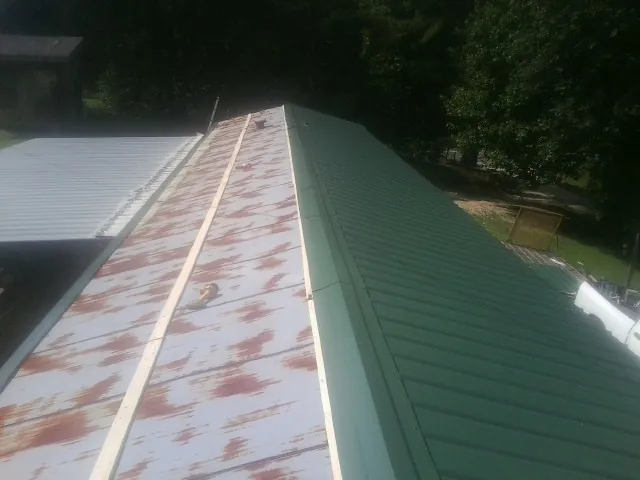 Old rusted panels beside newly installed green metal roofing — Wind Damage Roof Repair by Roofing Brothers in Tupelo
